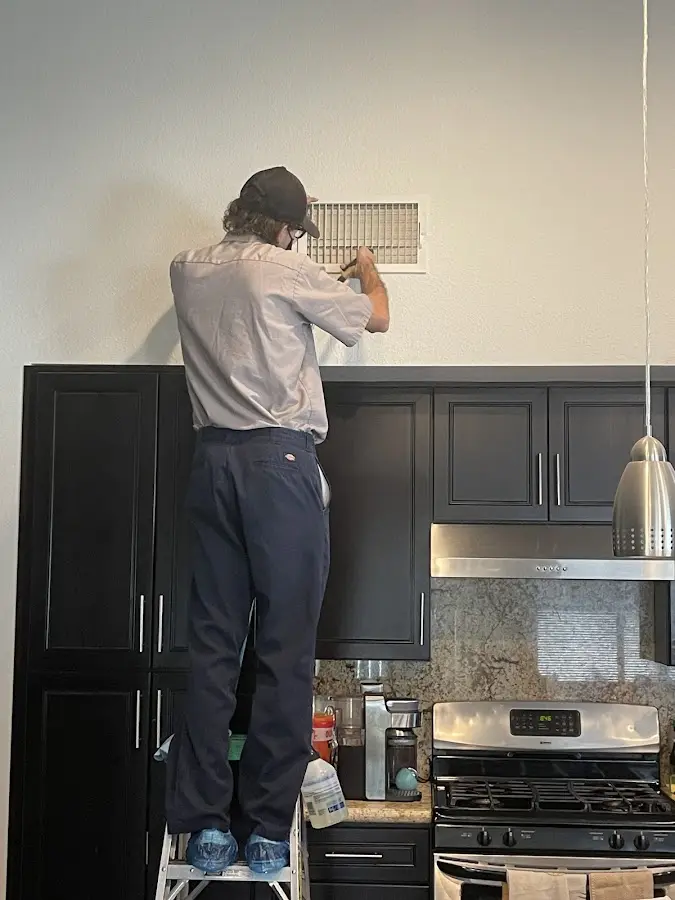 Technician inspecting an air vent during HVAC service in Ranson corporation